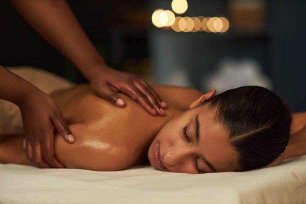 Woman receiving relaxing shoulder and back massage in Dubai spa with candles and soothing ambiance.